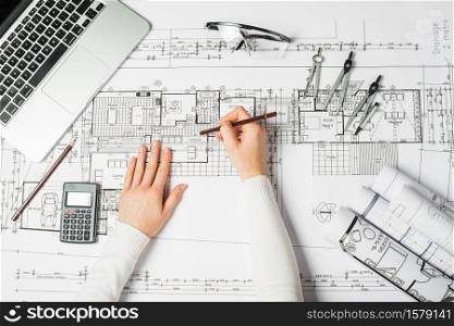 Hand over Construction plans with yellow helmet and drawing tools on blueprints. Hand over Construction plans with yellow helmet and drawing tools on blueprints .