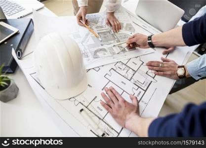 Hand over Construction plans with yellow helmet and drawing tools on blueprints. Hand over Construction plans with yellow helmet and drawing tools on blueprints .