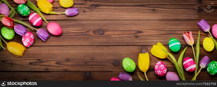 Hand-painted easter eggs with tulips on wooden background copy space for text. Easter eggs on woden background
