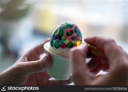 Hand painting of Easter eggs - close-up of hands and egg