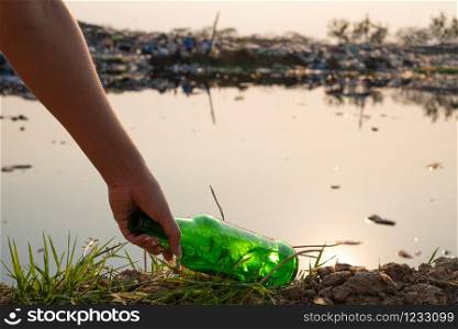 Hand-picking up green glass bottle and bottle at mountain large garbage background, These waste come from urban and industrial areas can not get rid of, Pile of stink and toxic residue