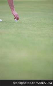 Hand placing ball on golf tee
