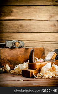 Hand planer with wooden sawdust. On a wooden background. High quality photo. Hand planer with wooden sawdust.