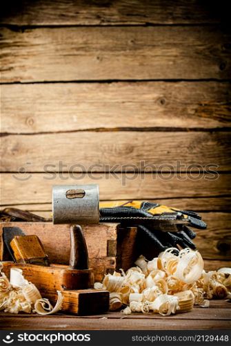 Hand planer with wooden sawdust. On a wooden background. High quality photo. Hand planer with wooden sawdust.
