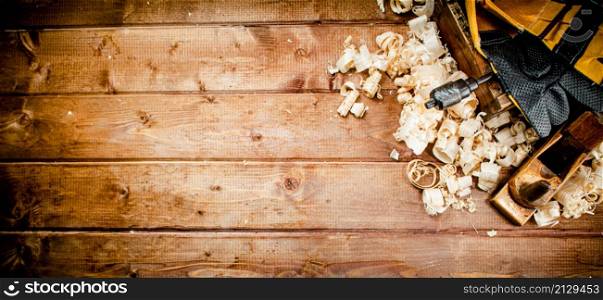 Hand planer with wooden sawdust. On a wooden background. High quality photo. Hand planer with wooden sawdust.