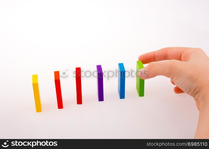 Hand playing with colored domino on white background