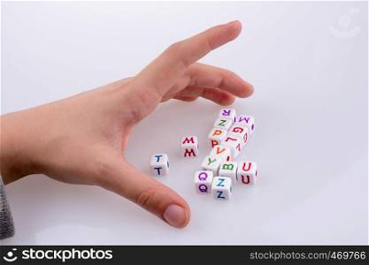 Hand playing with Letter cubes on a white background