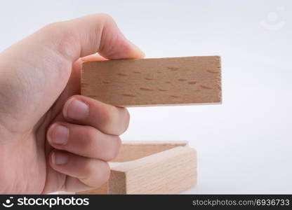 Hand playing with wooden building blocks on white background