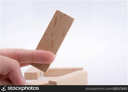 Hand playing with wooden building blocks on white background