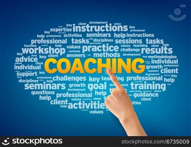 Hand pointing at a Coaching Word Cloud on blue background.