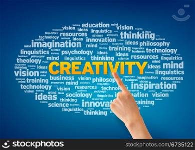 Hand pointing at a Creativity Word Cloud on blue background.