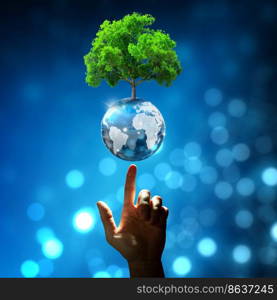 Hand pointing growing tree on crystal ball with technological convergence blue background. Innovative technology, Nature technology interaction, Environmental friendly, IT Ethics, and Ecosystem concept.