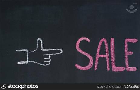 Hand pointing to the word Sale, written on a blackboard
