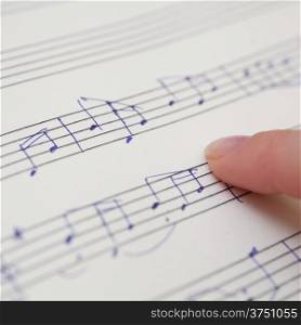 Hand pointing with pen to music book with handwritten notes