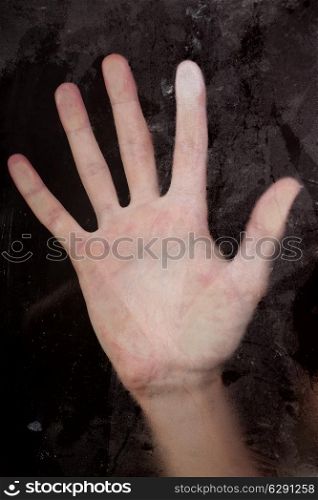 Hand pressed against dirty wet glass close