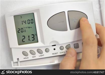 hand pressing button on digital thermostat