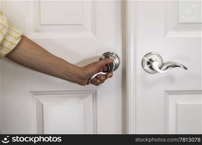 Hand pulling down chrome door handle on white panel door