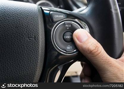 hand pushes Cruise control buttons on modern car and speed limitation