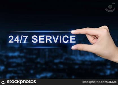 hand pushing 24 hours a day, 7 days a week service button on blurred blue background