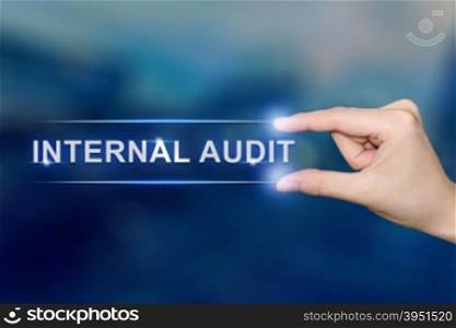 hand pushing internal audit button on blurred blue background