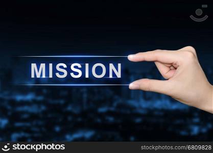 hand pushing mission button on blurred blue background