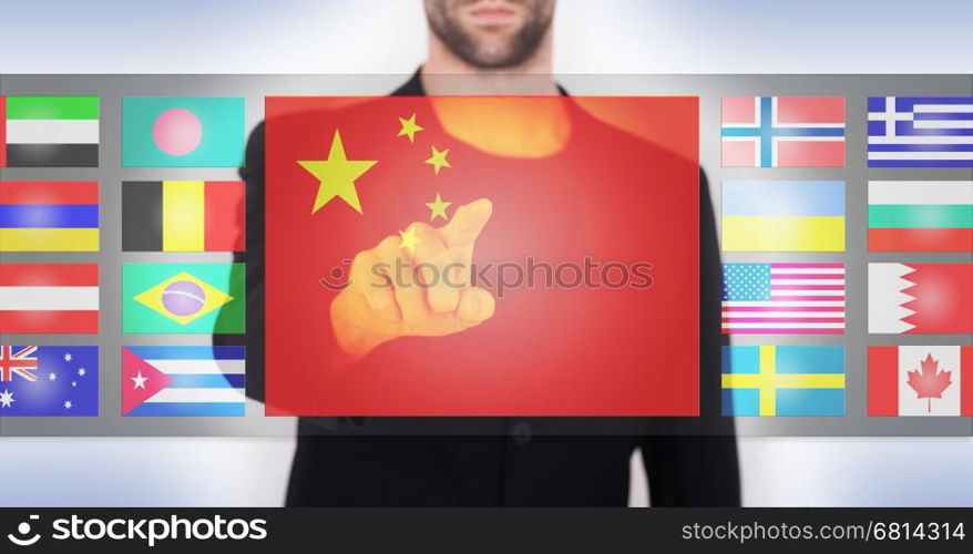 Hand pushing on a touch screen interface, choosing language or country, China