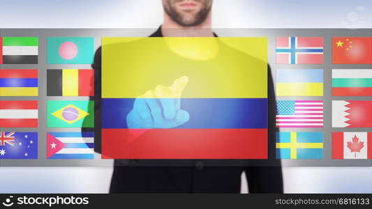 Hand pushing on a touch screen interface, choosing language or country, Colombia