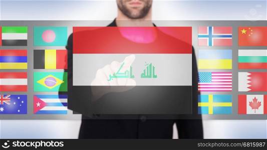 Hand pushing on a touch screen interface, choosing language or country, Iraq
