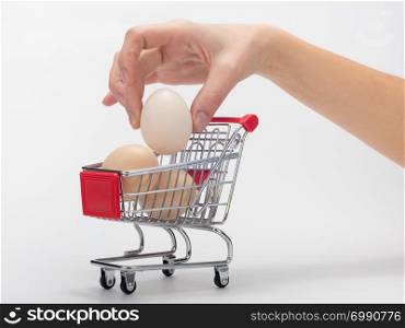 Hand puts chicken eggs in the grocery cart