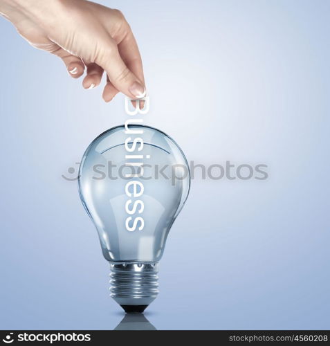 Hand putting a busines term into a light bulb