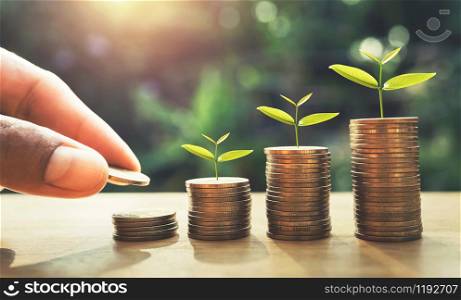 hand putting coins on stack with plant growing on money . finance and accounting concept