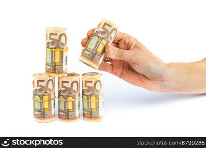 Hand putting down rolls of euro money isolated on white background