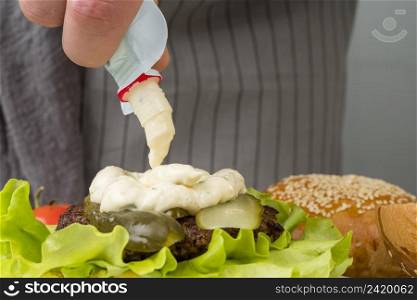 hand putting mayonnaise burger
