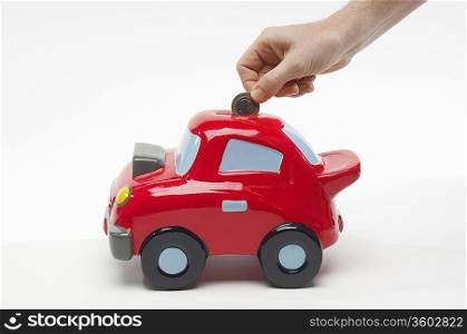 Hand Putting Money in Car Shaped Piggy Bank