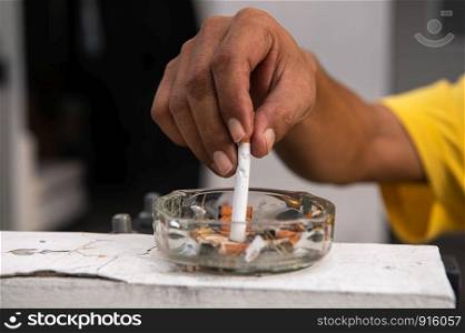 Hand putting out cigarette and destroy in ashtray at outdoor in front of house. Healthy and people concept. World No Tobacco Day theme
