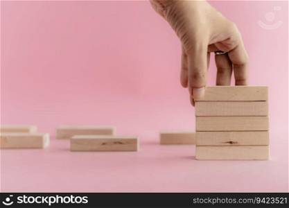 Hand putting the wooden toy on pink background for leisure activities concept
