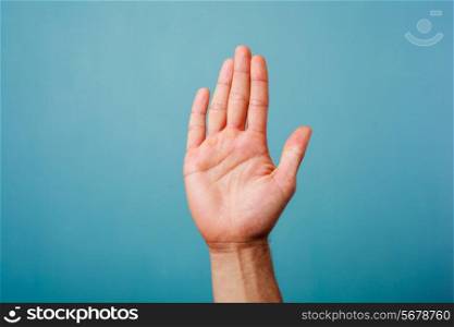 Hand raised against a blue background