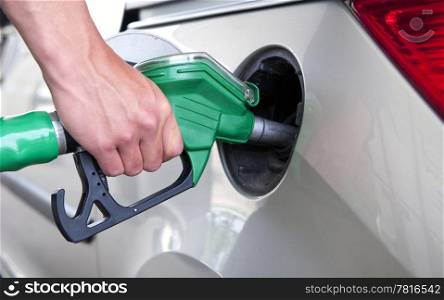 Hand, refuelling a passenger car, holding a green fuel pump