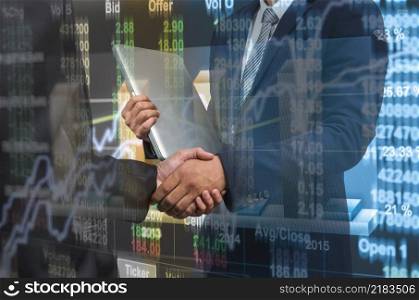 Hand shake between businessman over Stock market chart,Closeup Stock market exchange data on LED display, business trading concept