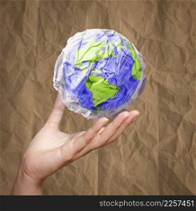 hand showing crumpled world paper symbol on crumpled recycle paper as concept