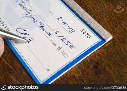 Hand Signing Check Paper Payment on top of Desk