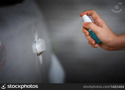 hand spraying alcohol to cleaning car door handle for protect from infection of virus and germ Covid-19 coronavirus