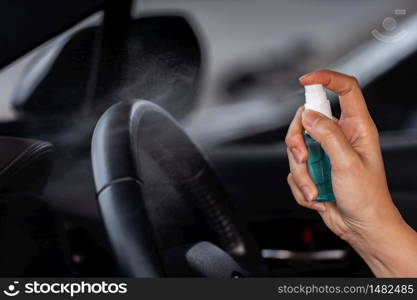 hand spraying alcohol to cleaning car steering wheel for protect from infection of virus and germ Covid-19 coronavirus