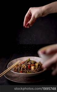 hand sprinkling salt bowl noodles with vegetables
