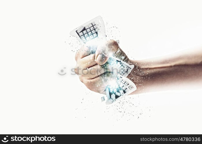 Hand squeezing keyboard. Close-up image of human hand clutching keyboard
