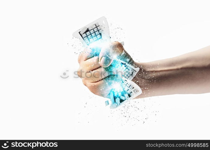 Hand squeezing keyboard. Close-up image of human hand clutching keyboard