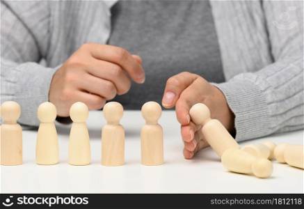 hand stops the fall of figurines of men on a white background. Concept of a strong and courageous personality capable of withstanding unequal difficulties. Strong business, control of the situation