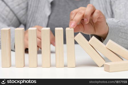 hand stops the fall of wooden blocks on a white background. Concept of a strong and courageous personality capable of withstanding unequal difficulties. Strong business, control of the situation