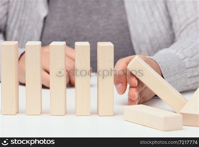 hand stops the fall of wooden blocks on a white background. Concept of a strong and courageous personality capable of withstanding unequal difficulties. Strong business, control of the situation