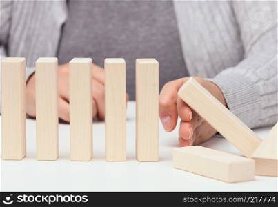 hand stops the fall of wooden blocks on a white background. Concept of a strong and courageous personality capable of withstanding unequal difficulties. Strong business, control of the situation